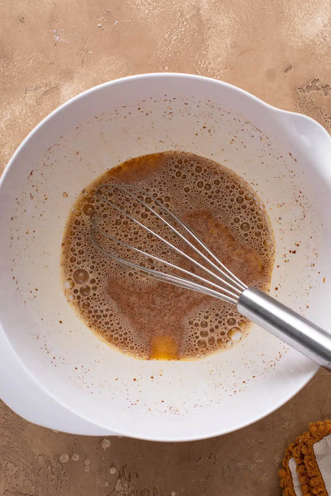 Eggs whisked with vinegar and cinnamon in a mixing bowl.