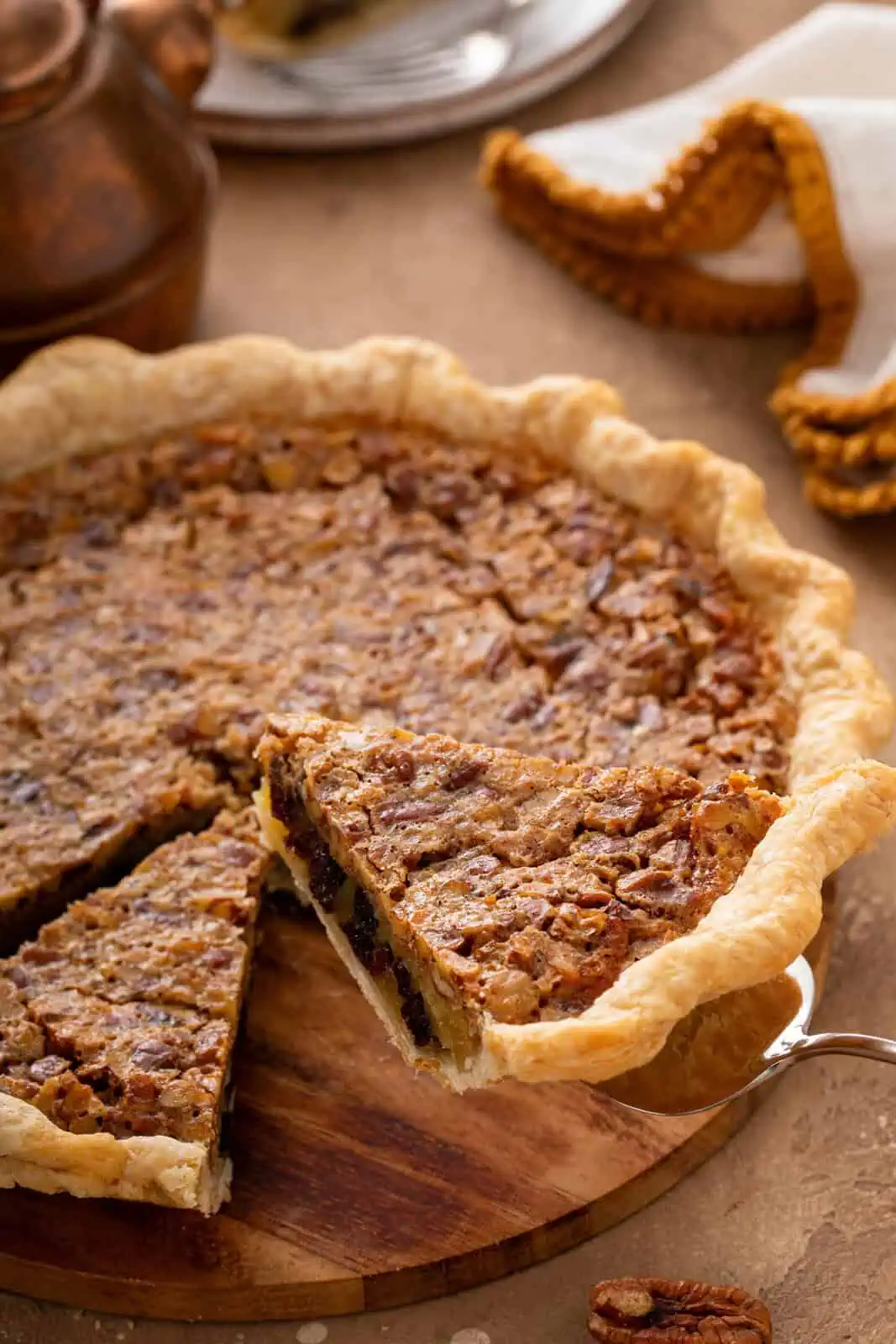 Pie server lifting up a slice of pecan raisin pie.