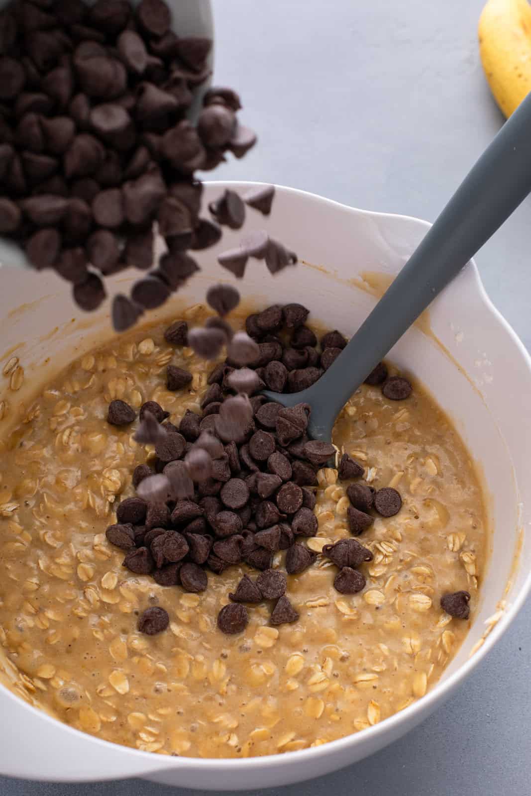 Chocolate chips being added to banana oat muffin batter.