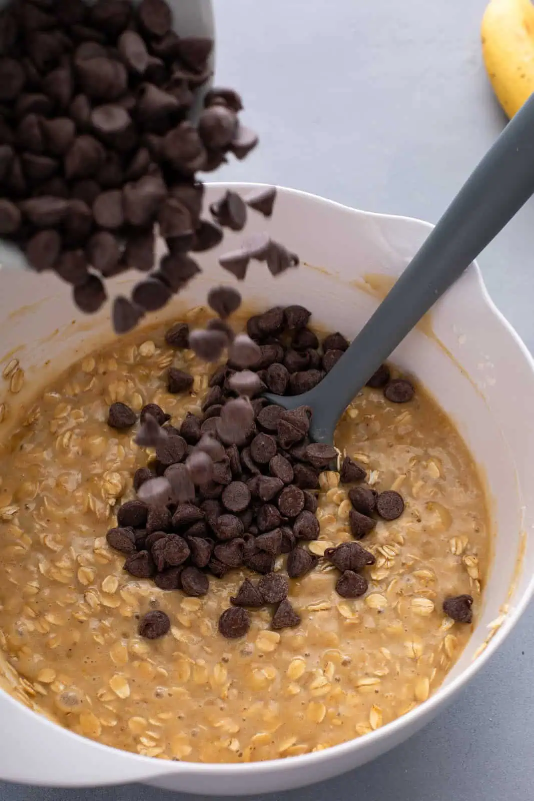 Chocolate chips being added to banana oat muffin batter.