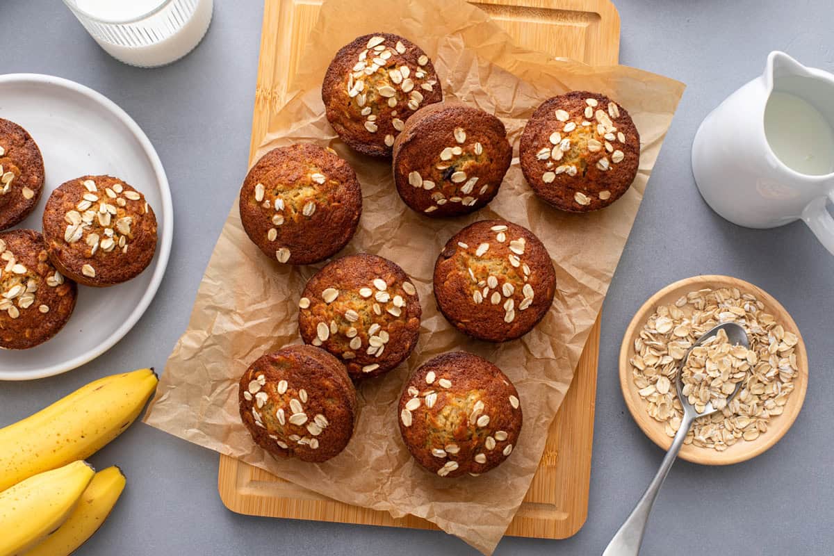 Overhead view of banana oat muffins scattered on a piece of parchment paper.