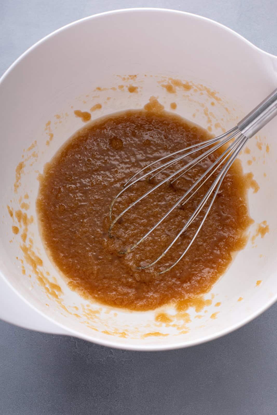 Sugars and melted butter whisked together in a white bowl.