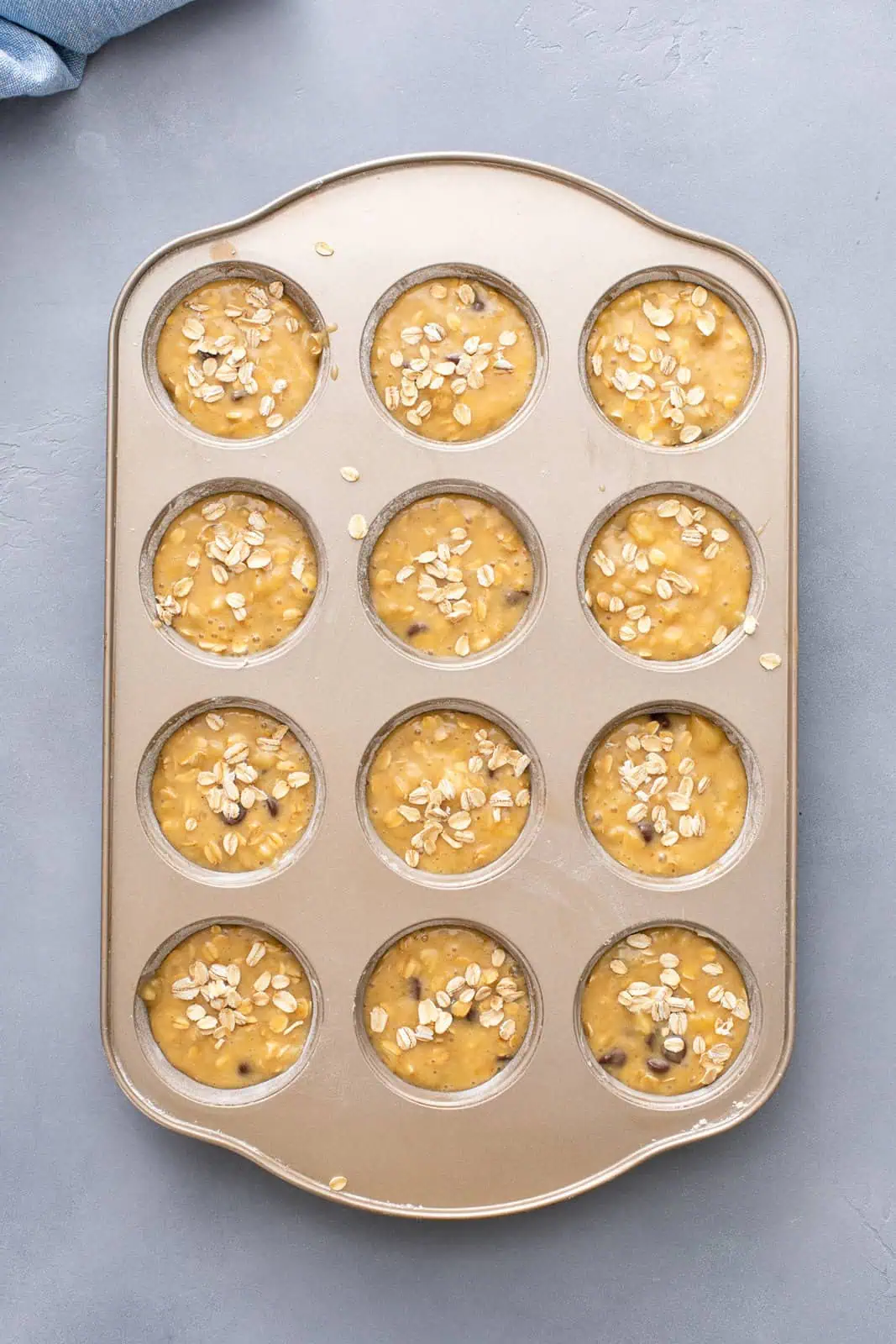 Unbaked banana oat muffins in a muffin tin, ready to go in the oven.