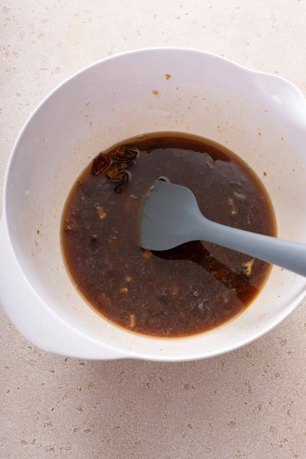 Wet ingredients for date nut bread mixed in a white bowl.