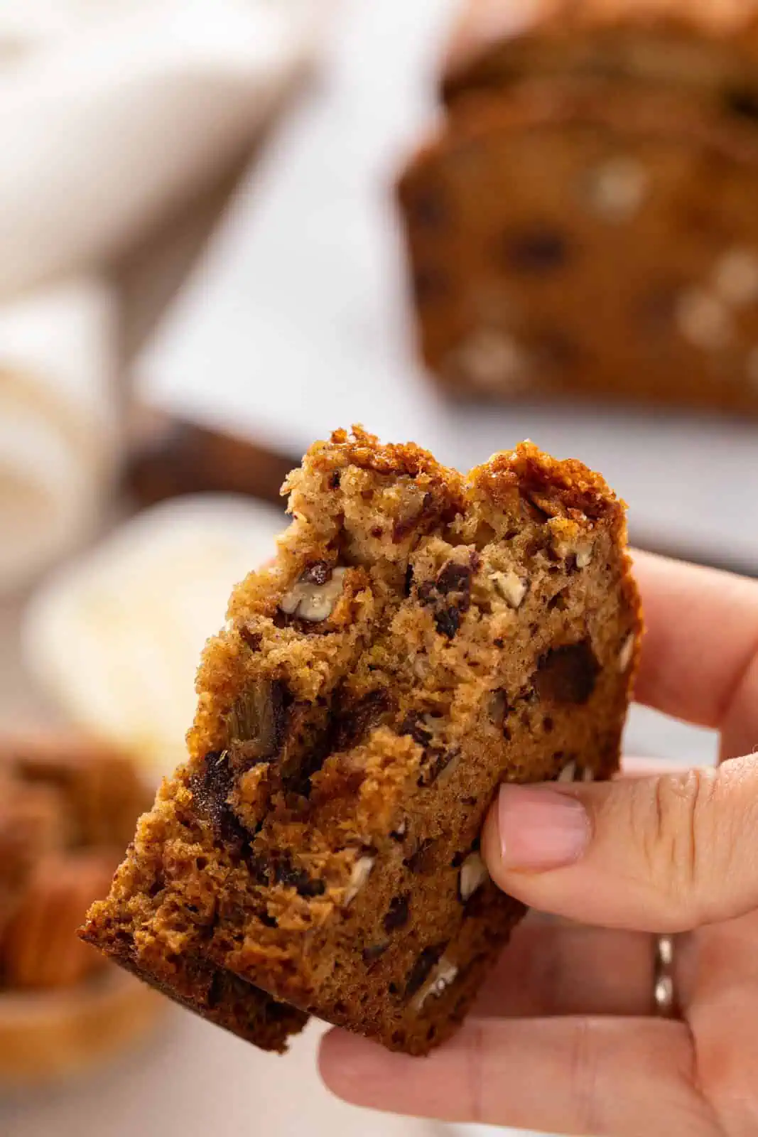 Hand holding a halved piece of date nut bread.