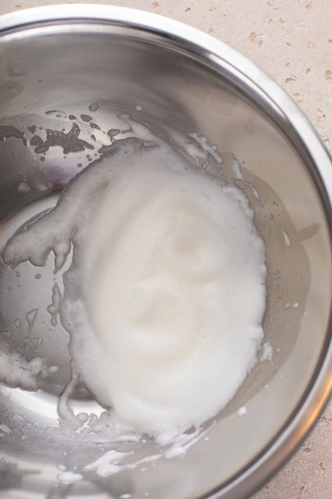 Whipped egg white in a metal bowl.