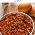 Shallow white bowl filled with sloppy joe meat on a wooden board next to hamburger buns. Text overlay includes recipe name.