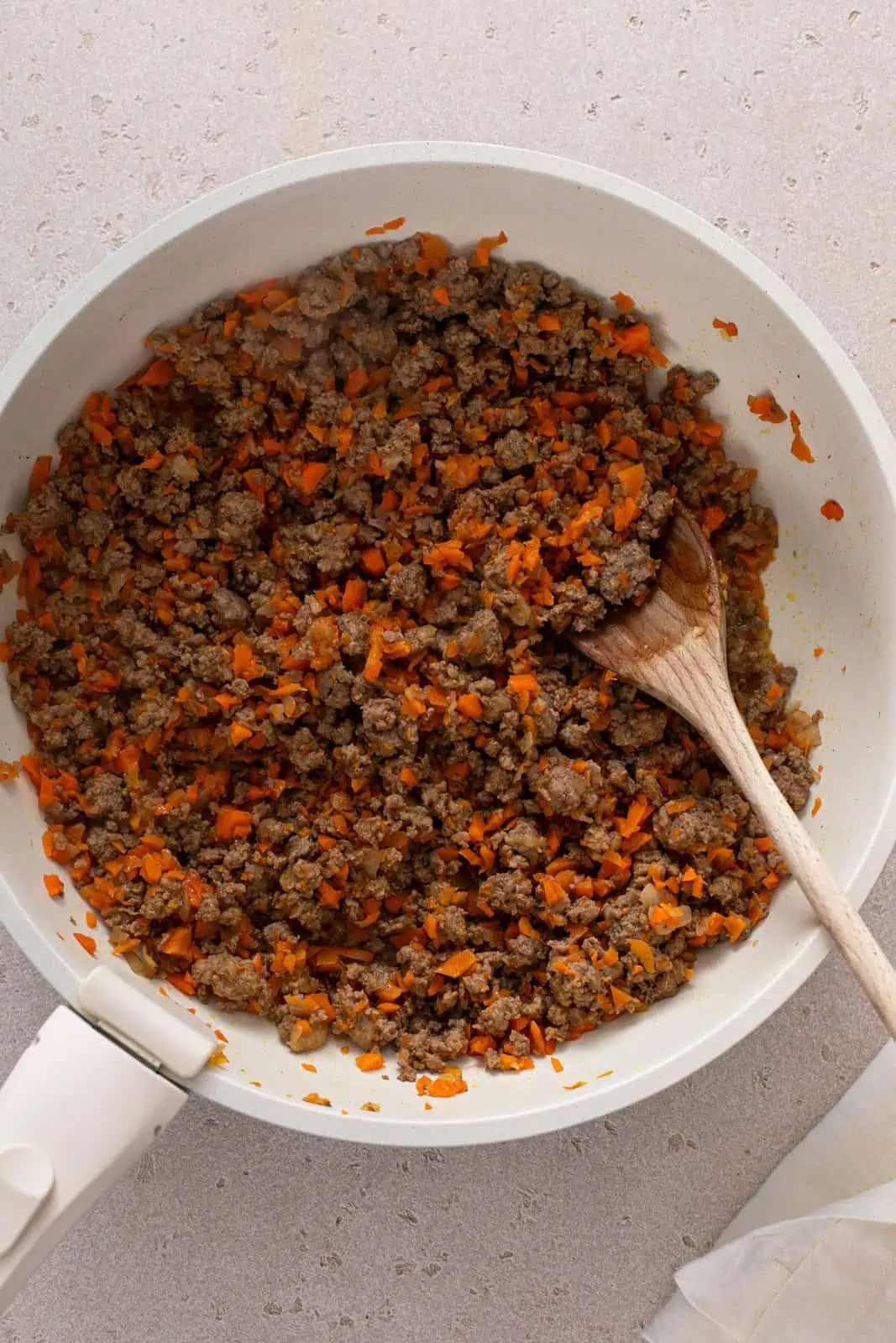 Cooked ground beef, carrots, and onions in a skillet.