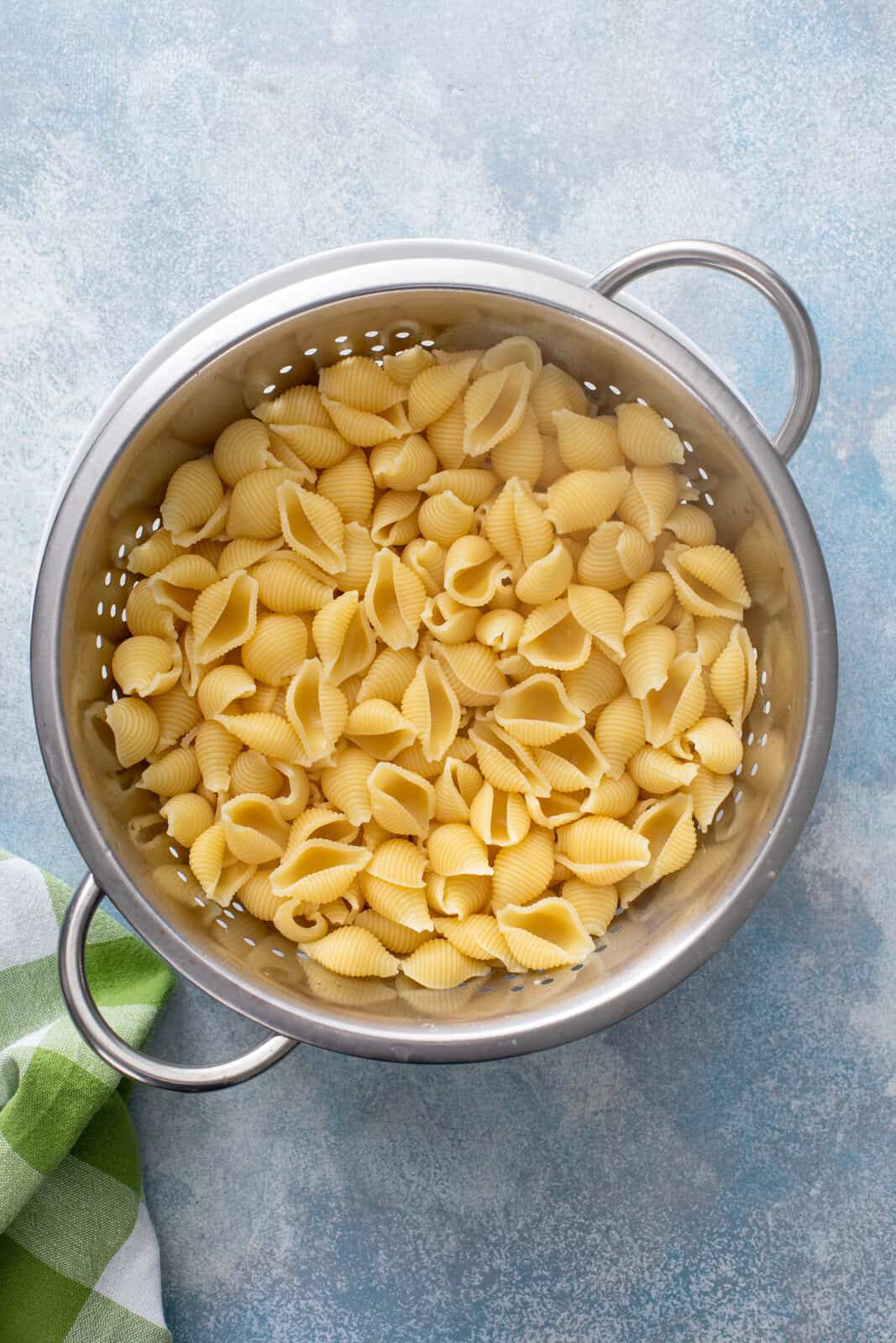 Cooked and drained pasta shells in a metal colander.