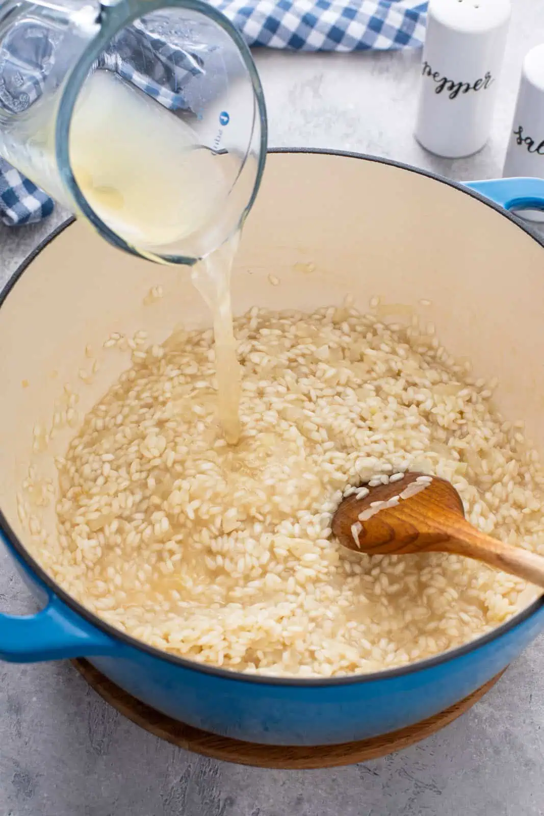 Hot chicken stock being added to arborio rice in a dutch oven.