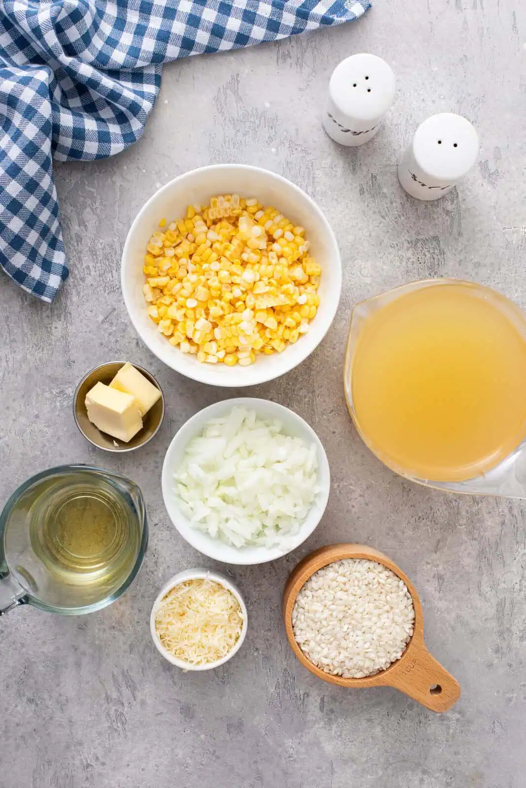 Ingredients for sweet corn risotto arranged on a gray countertop.