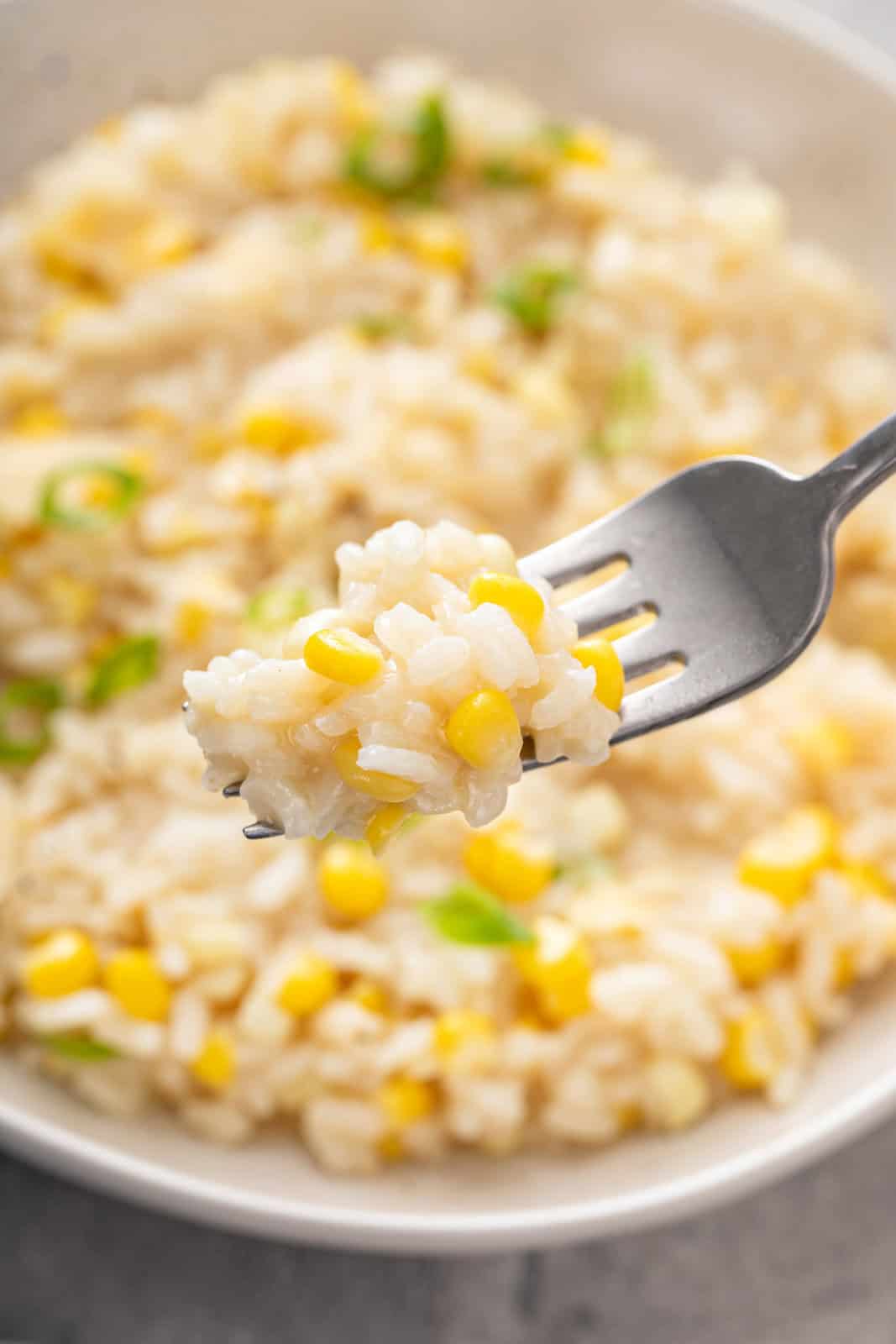 Fork holding up a bite of sweet corn risotto.