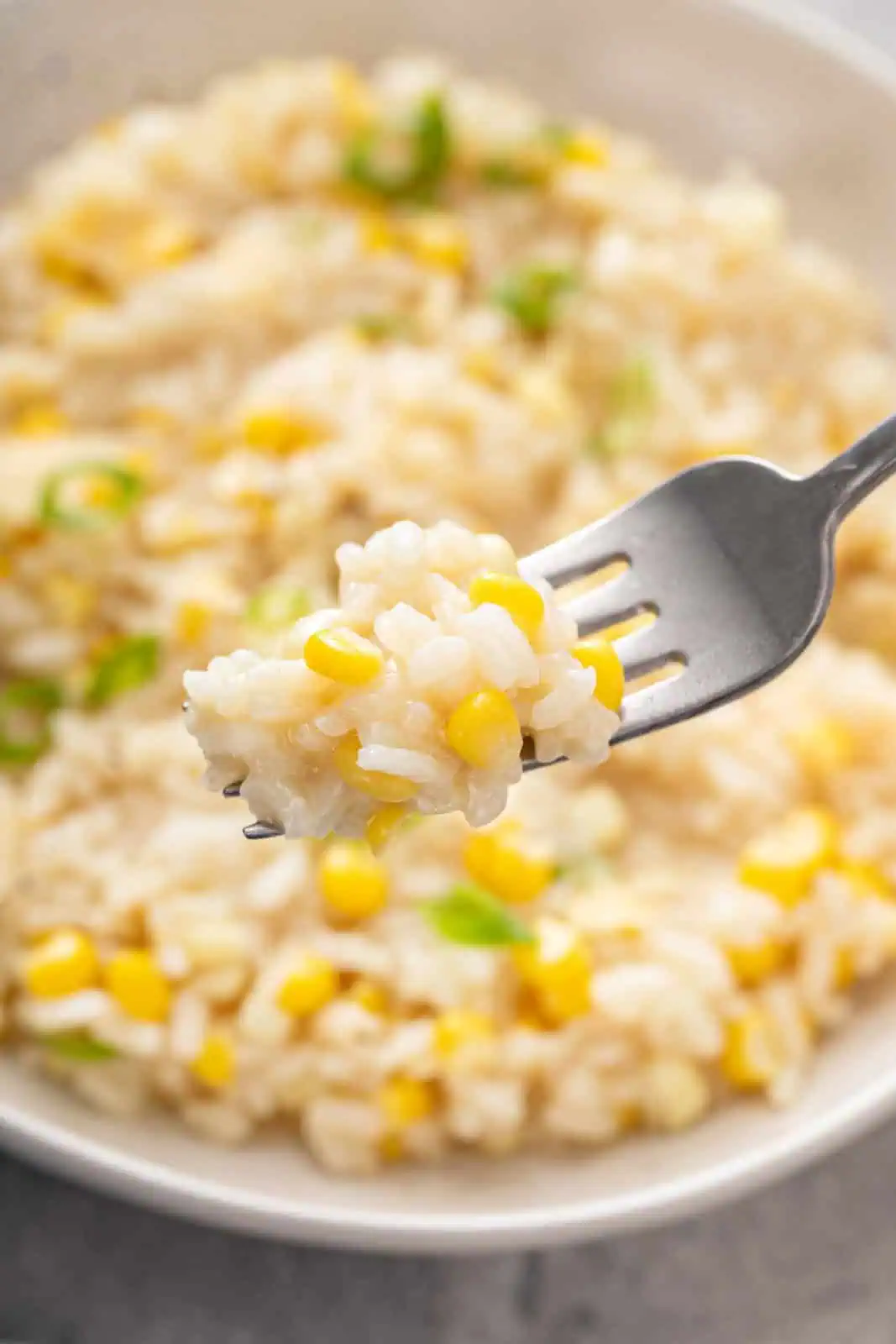 Fork holding up a bite of sweet corn risotto.