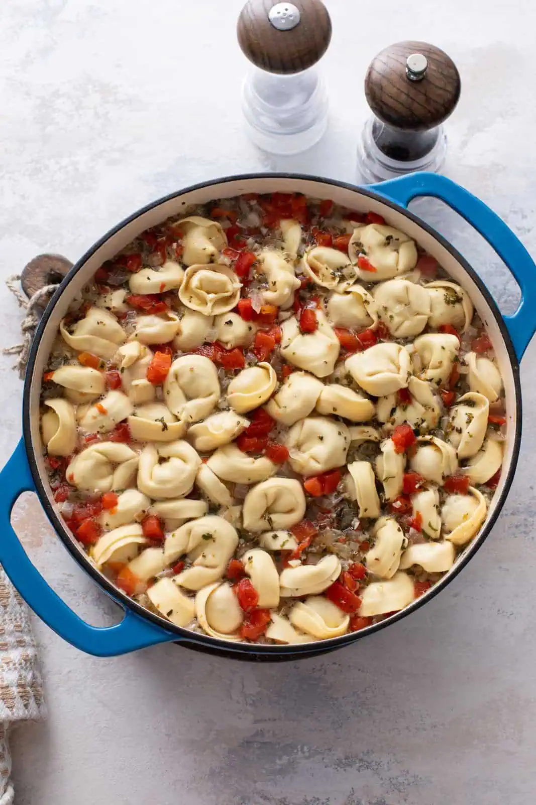 Tortellini cooking in a tomatoey broth in a dutch oven.