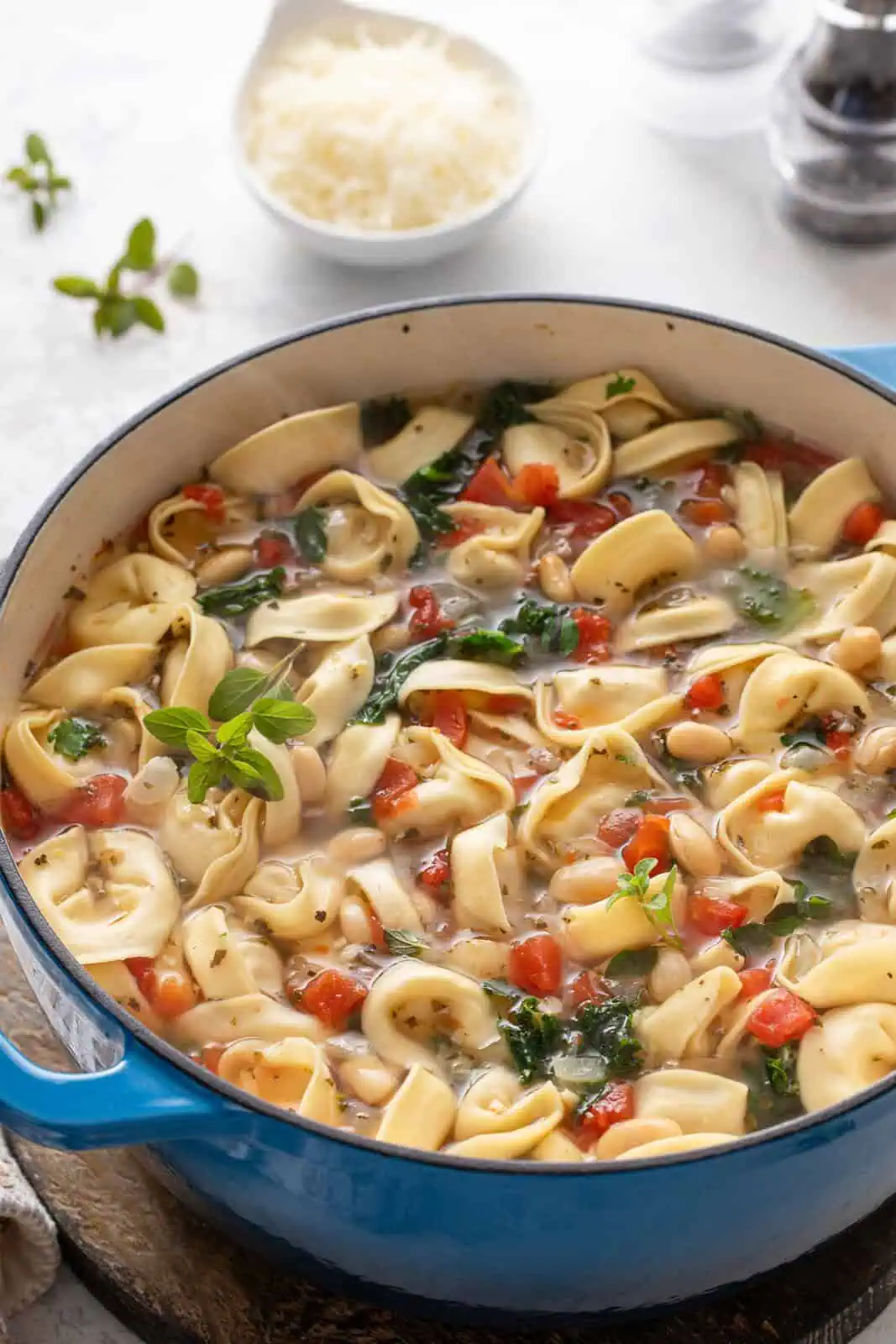 Cooked tortellini soup in a blue dutch oven.