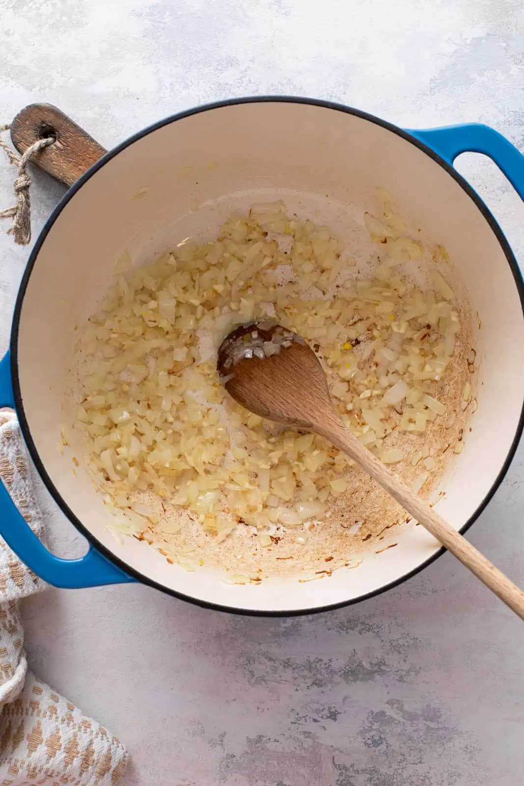 Onion and garlic being sauteed in a dutch oven.