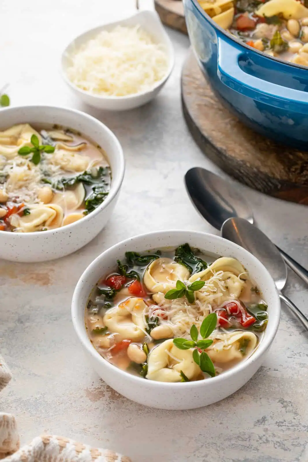 Two bowls of easy tortellini soup next to a pot of the soup.