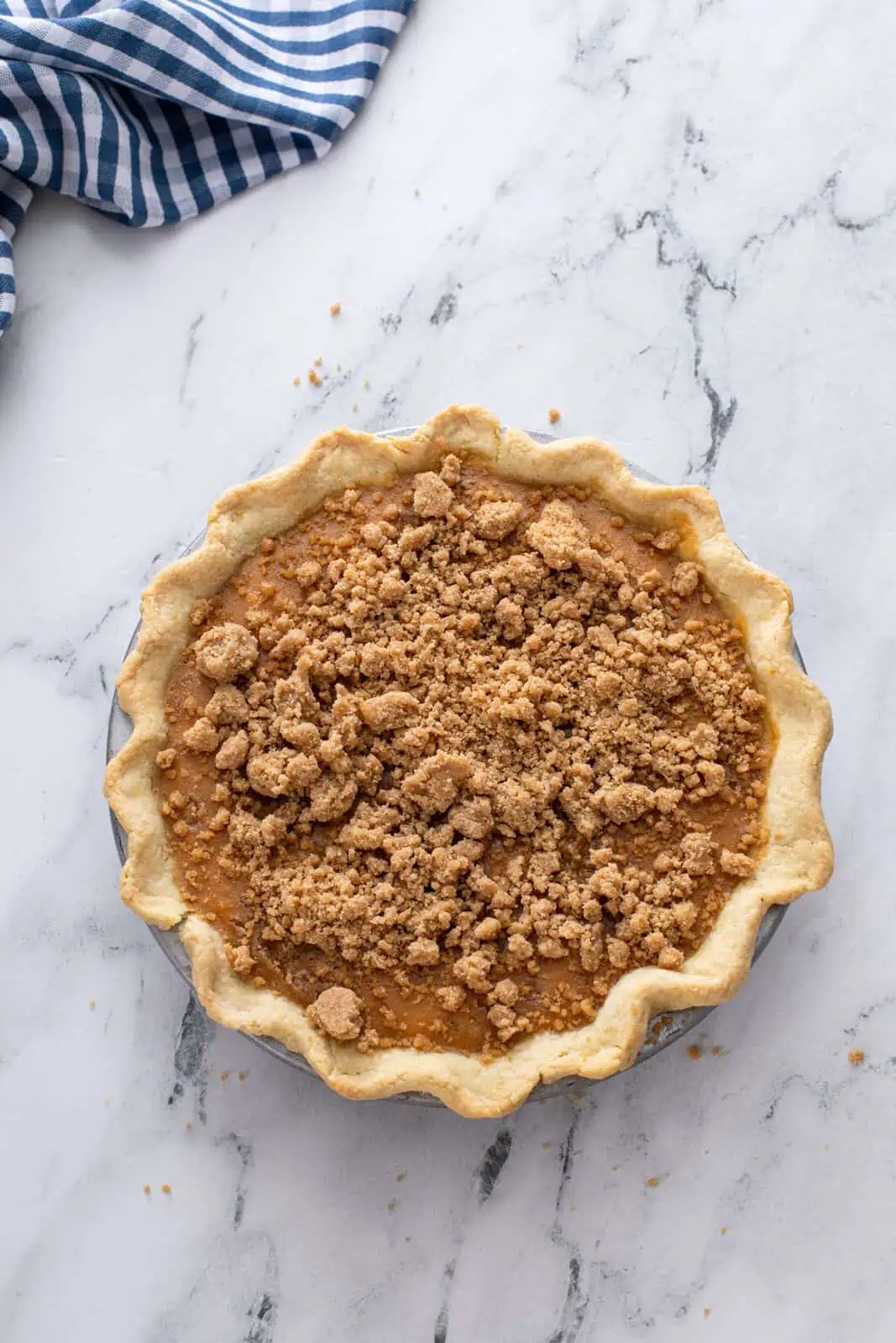 Adding streusel topping to partially-baked sweet potato pie.