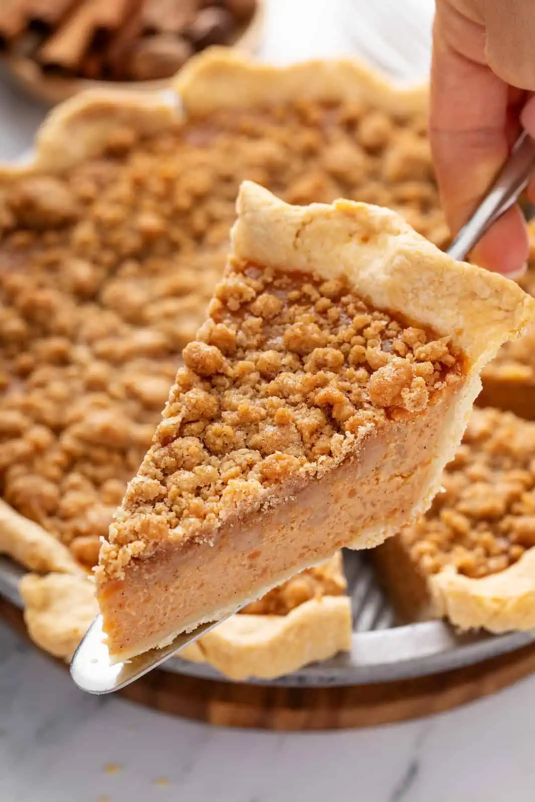 Pie server holding up a slice of sweet potato pie.