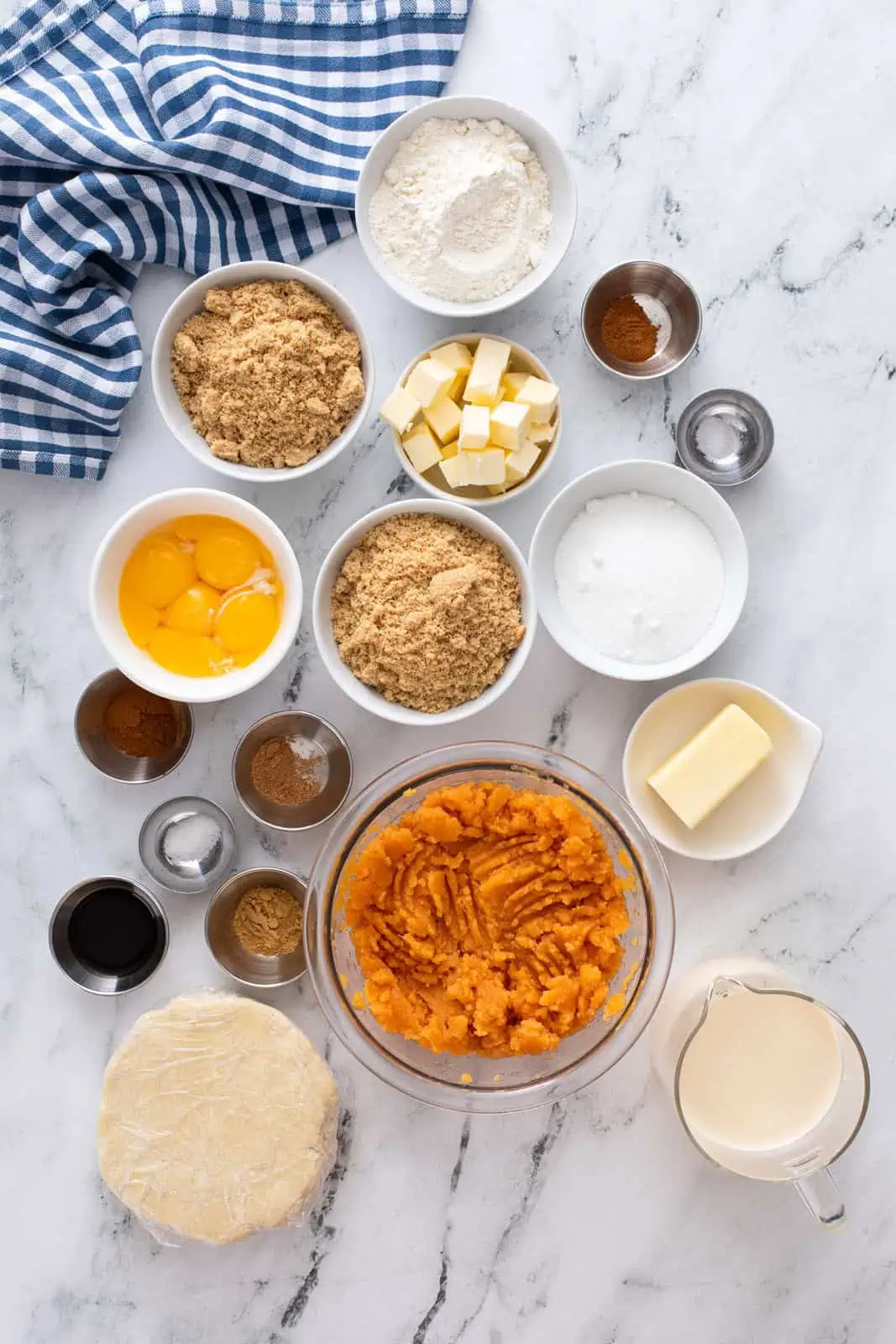 Ingredients for sweet potato pie arranged on a marble countertop.