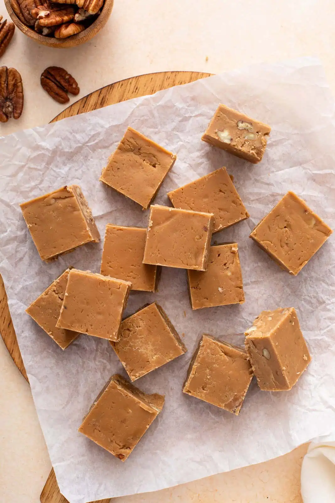 Brown sugar fudge cut into squares and scattered on a piece of parchment paper.