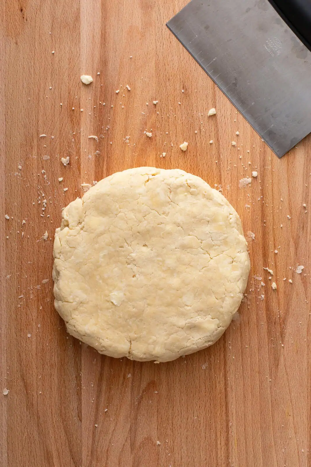 Disk of pie dough on a wooden board.