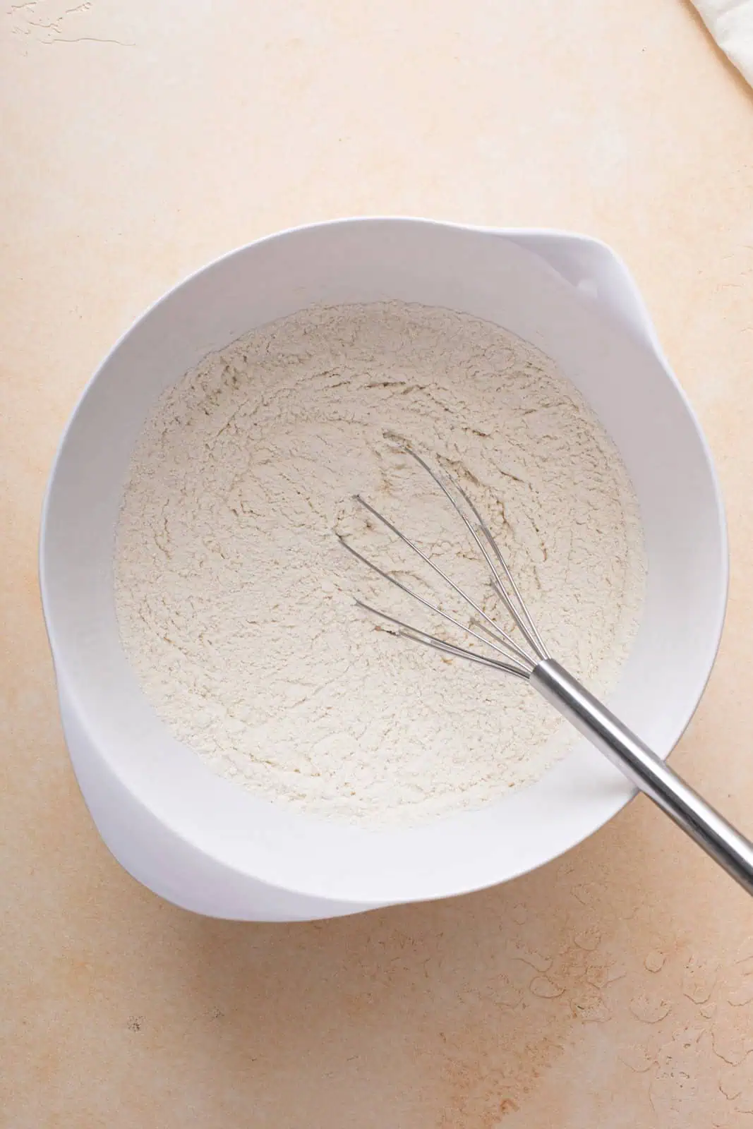 Flour and salt whisked in a white bowl.