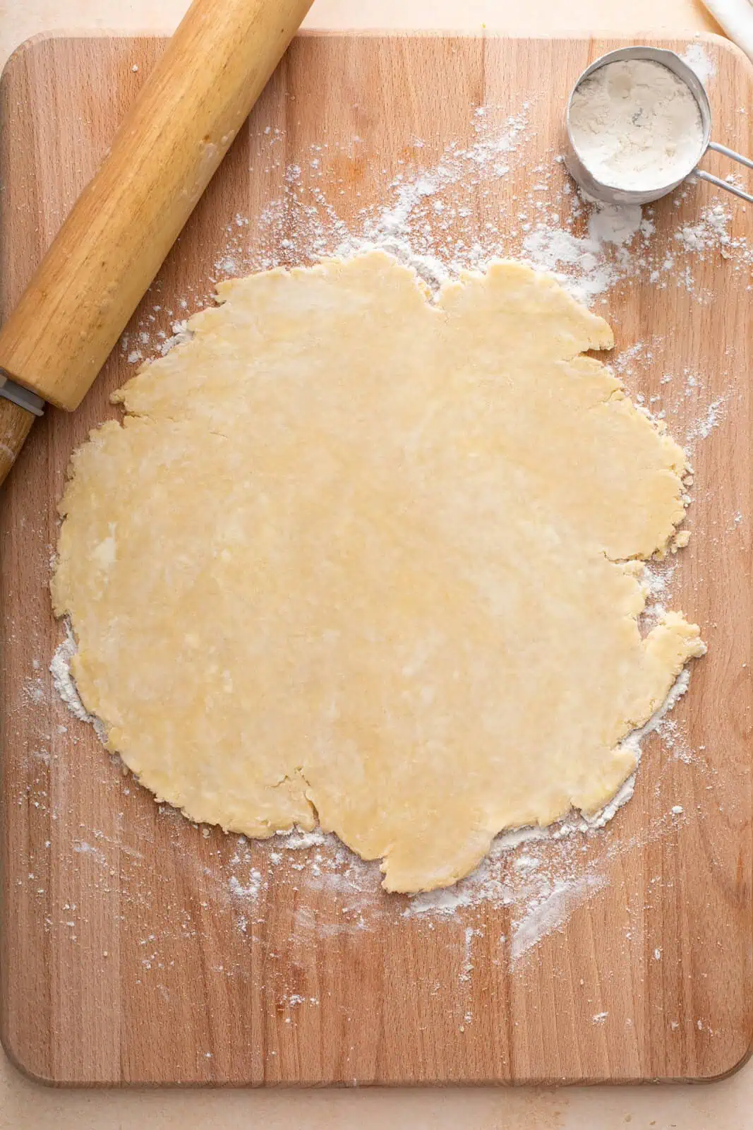 Rolled out pie dough on a wooden board.