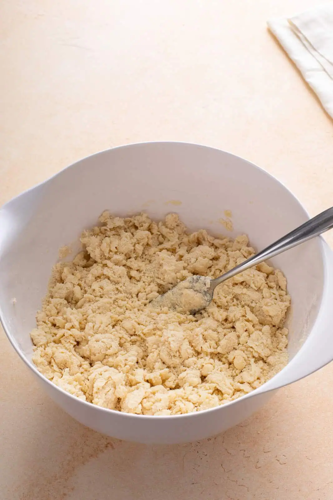 Fork mixing together pie dough in a white bowl.