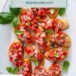 Overhead view of slices of tomato bruschetta on a white platter. Text overlay includes recipe name.