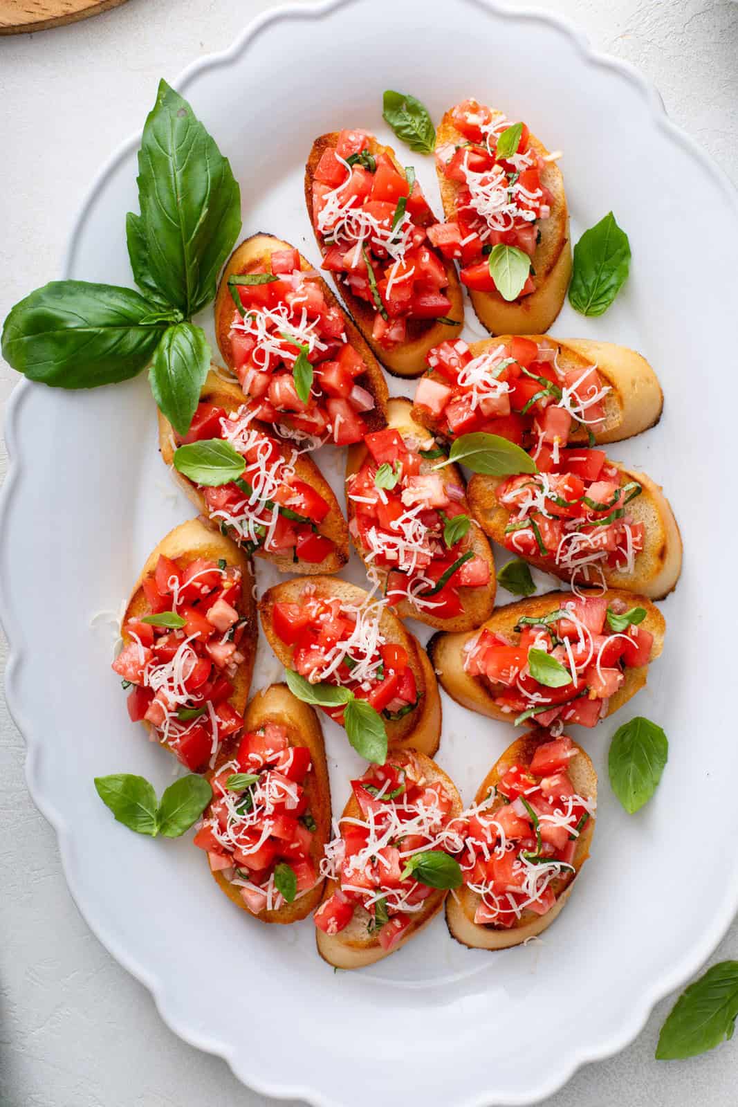 Overhead view of slices of tomato bruschetta on a white platter.