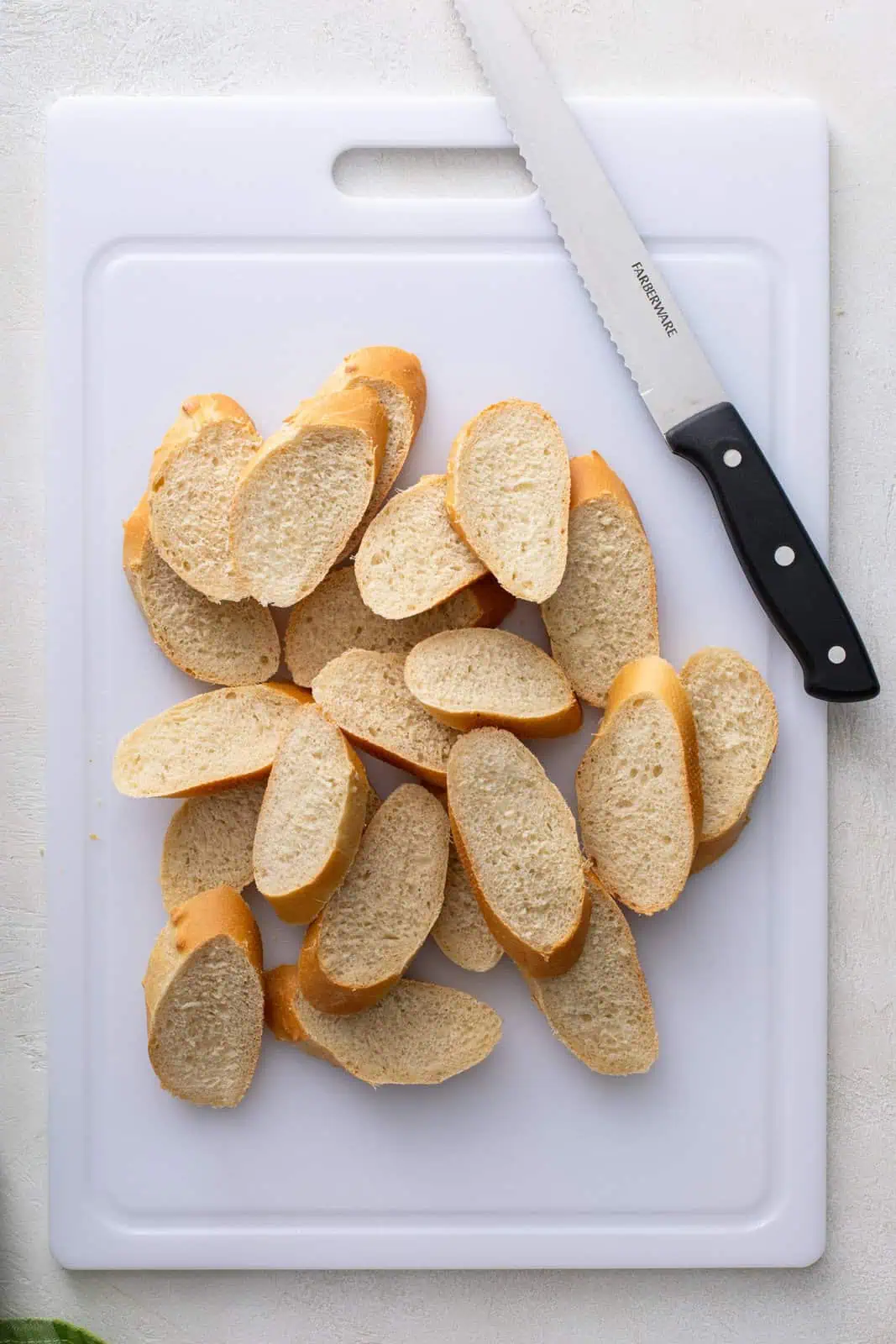 Sliced baguette pieces on a white cutting board.