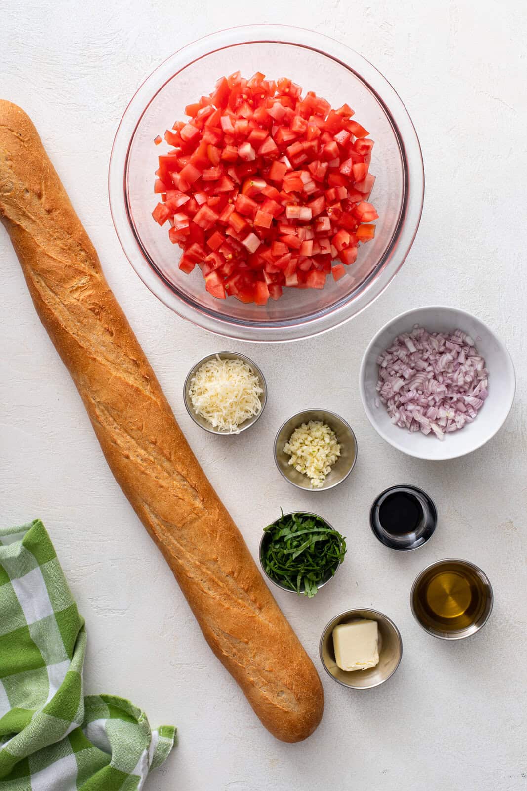 Ingredients for tomato bruschetta arranged on a countertop.