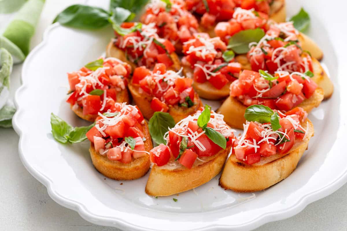 Slices of tomato bruschetta arranged on a white platter.