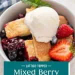 Spoon in a bowl of berry cobbler topped with a scoop of vanilla ice cream. Text overlay includes recipe name.