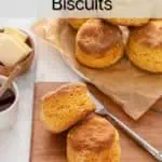 Two sweet potato biscuits on a wooden board with more biscuits in the background. Text overlay includes recipe name.