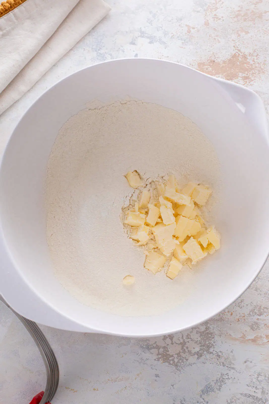 Cubes of cold butter added to a bowl of flour.