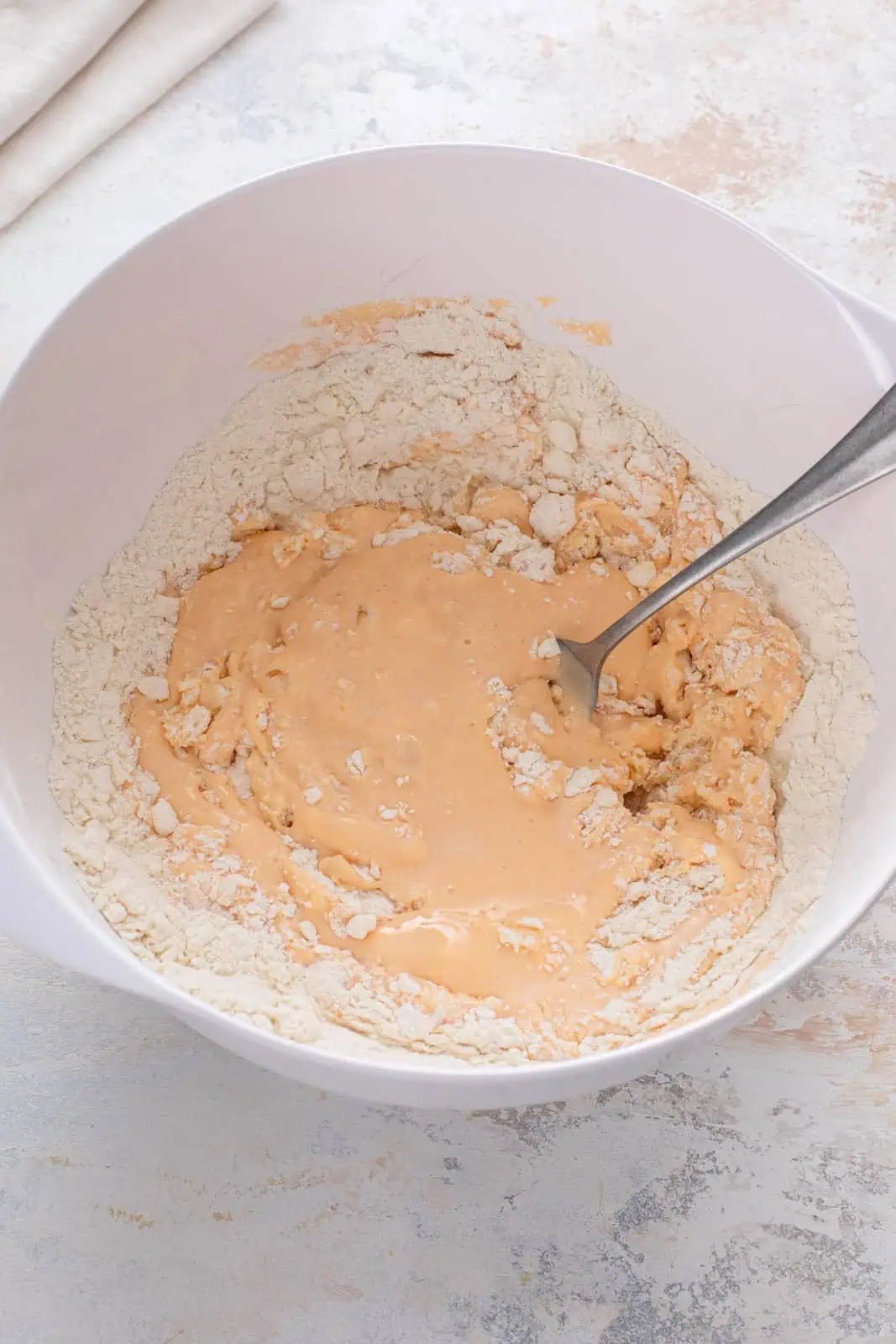 Wet ingredients for sweet potato biscuits added to flour mixture in a white bowl.