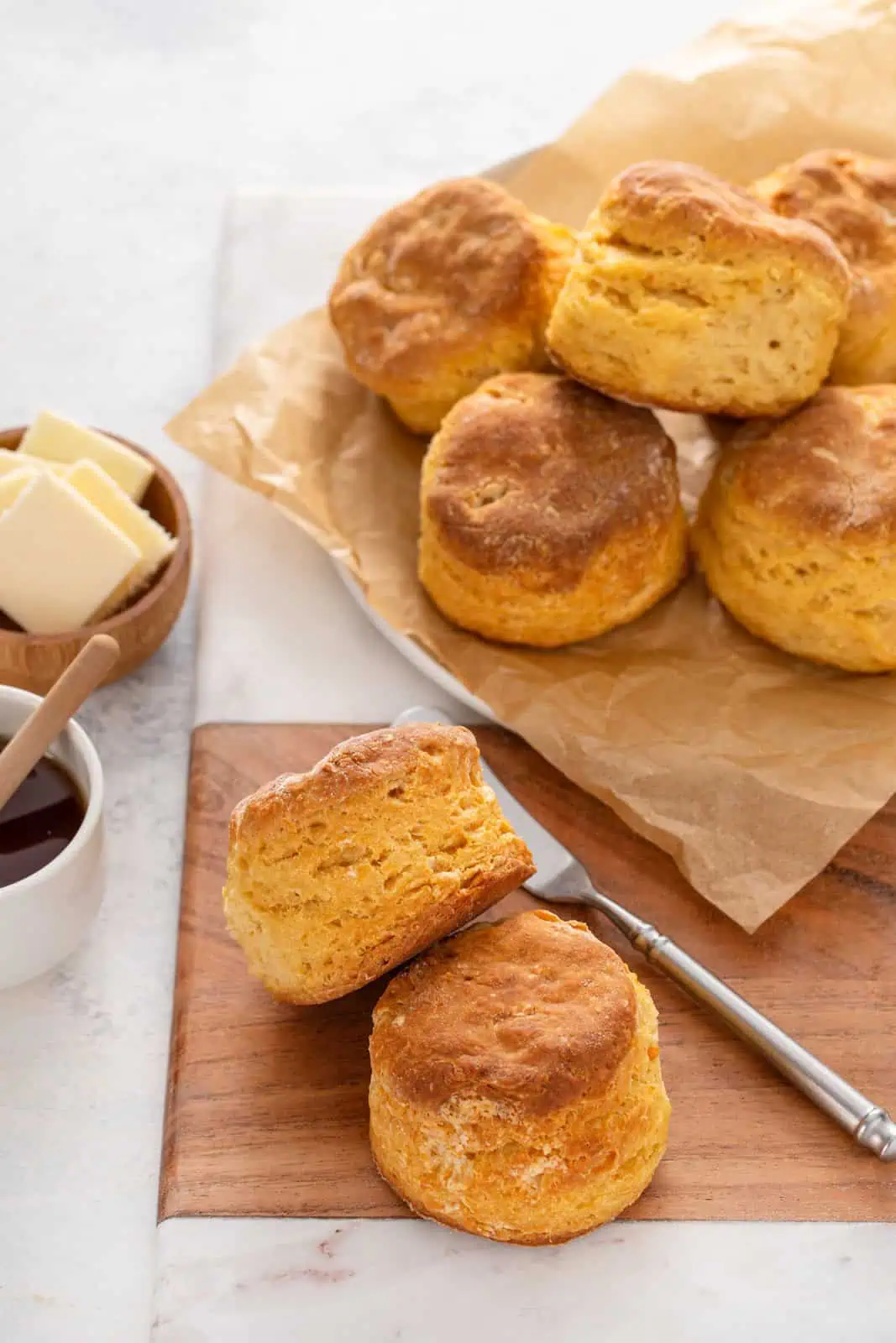 Two sweet potato biscuits on a wooden board with more biscuits in the background.