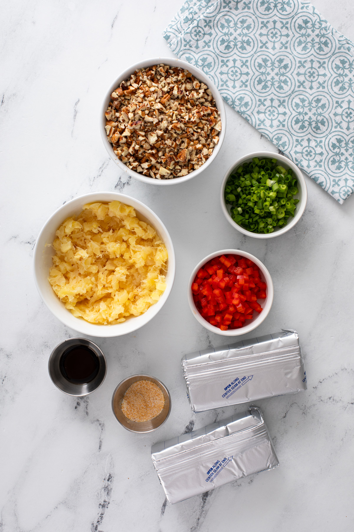 Ingredients for pineapple pecan cheese ball arranged on a countertop.