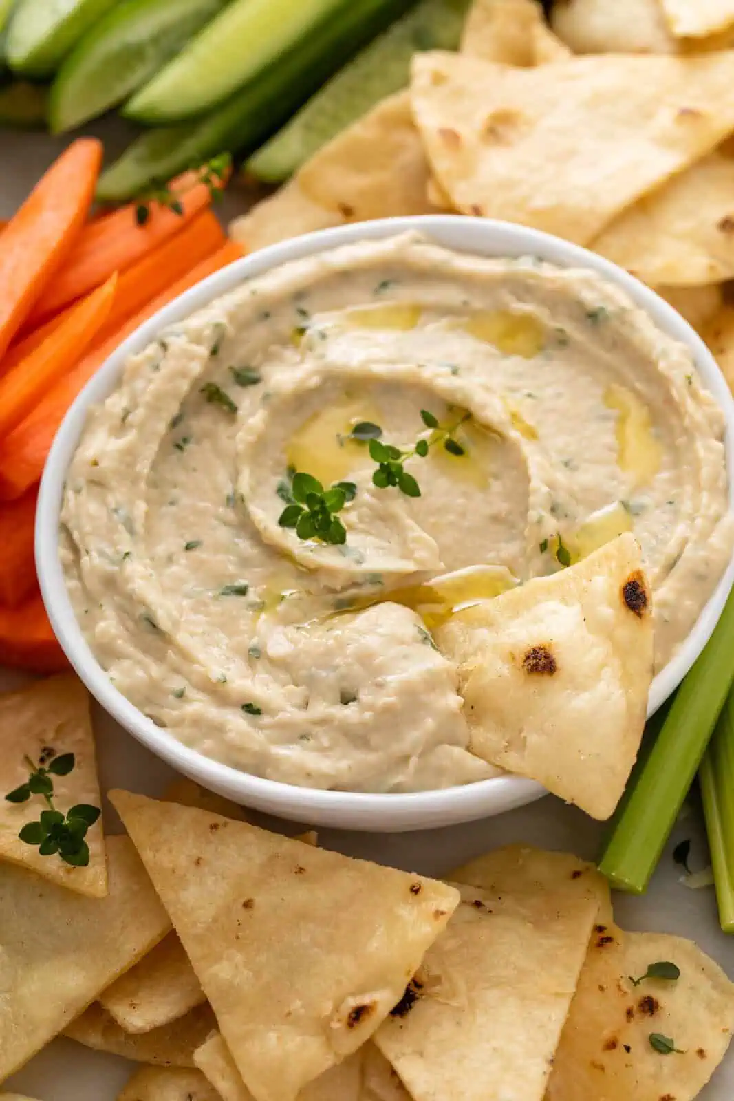 Pita chip in a bowl of white bean dip.