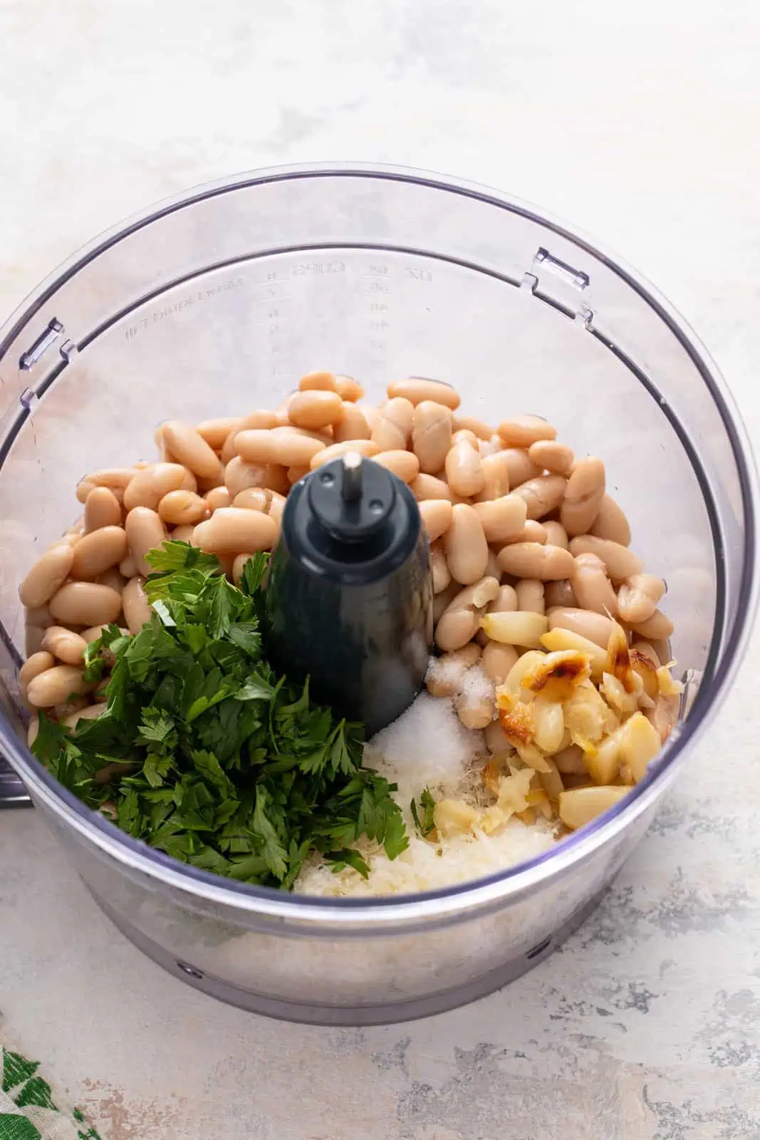 Ingredients for white bean dip added to the bowl of a food processor.