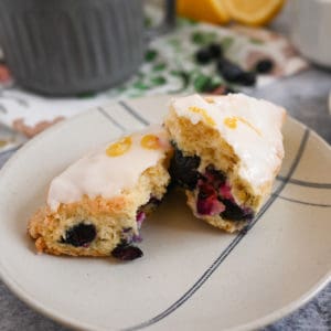 Halved blueberry lemon scone set on a cream and blue plate.