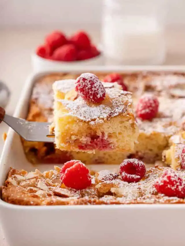 Cake server lifting a slice of raspberry almond coffee cake out of a cake pan.