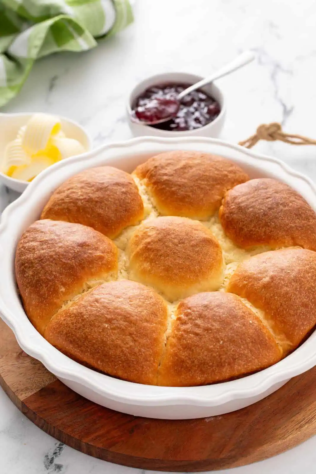 Pan of no-knead refrigerator rolls set on a wooden board.