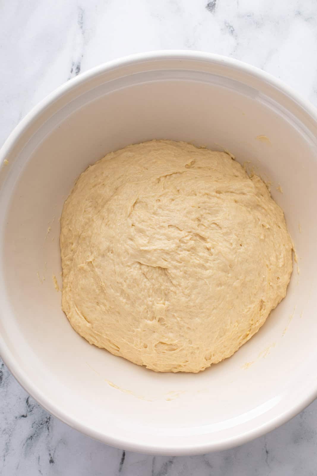 Yeast dough in a ceramic mixing bowl, ready to rise.