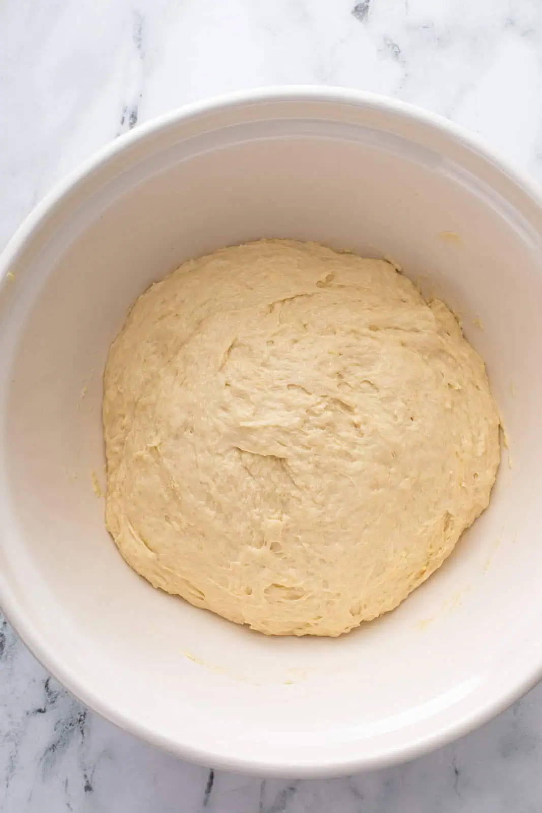 Yeast dough in a ceramic mixing bowl, ready to rise.