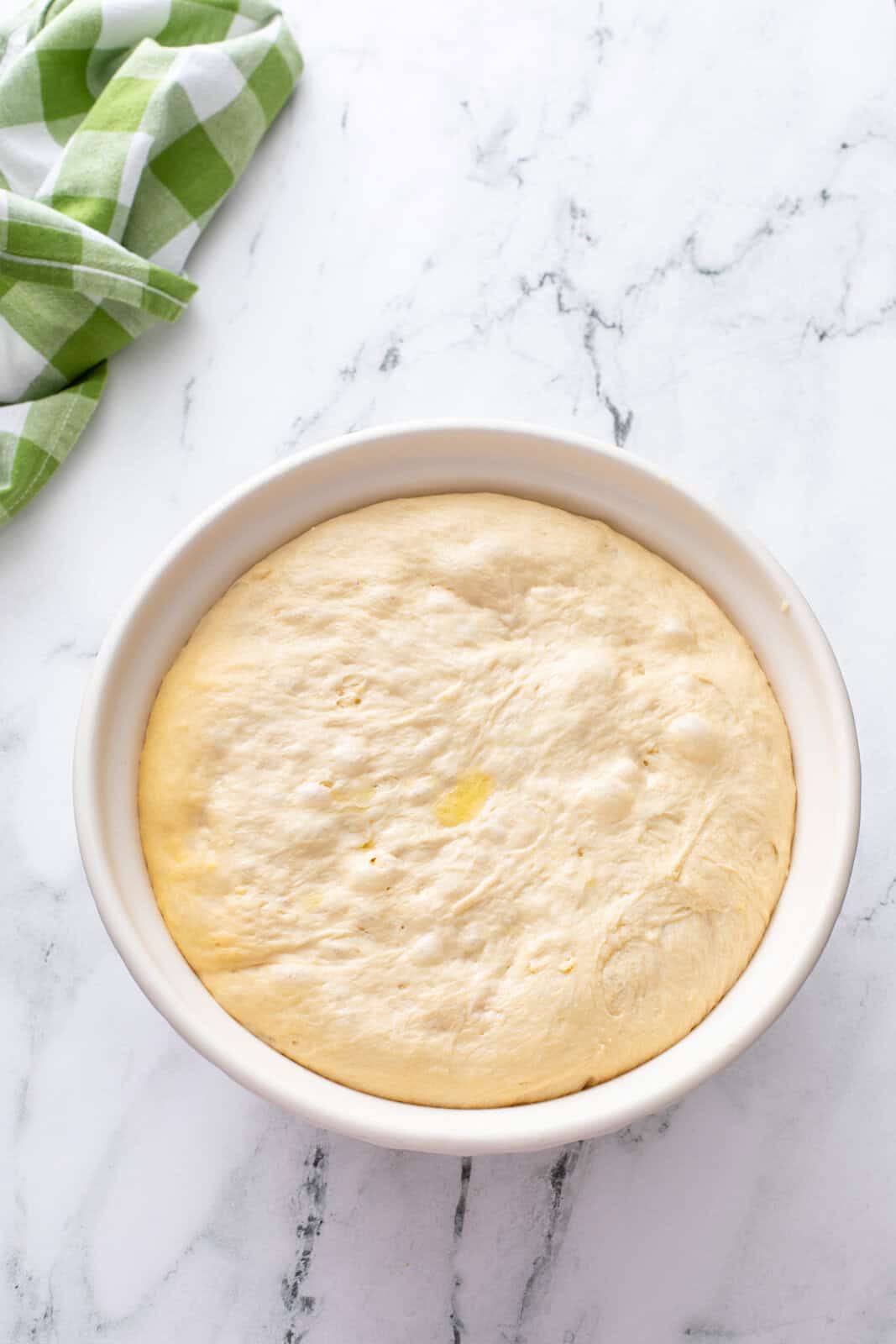 Risen yeast dough in a ceramic mixing bowl.