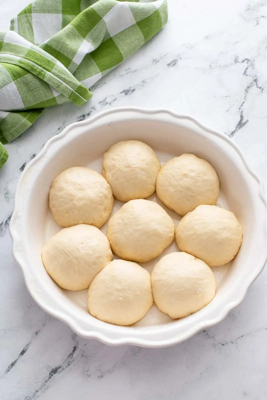 Shaped refrigerator rolls in a pan, ready to rise.