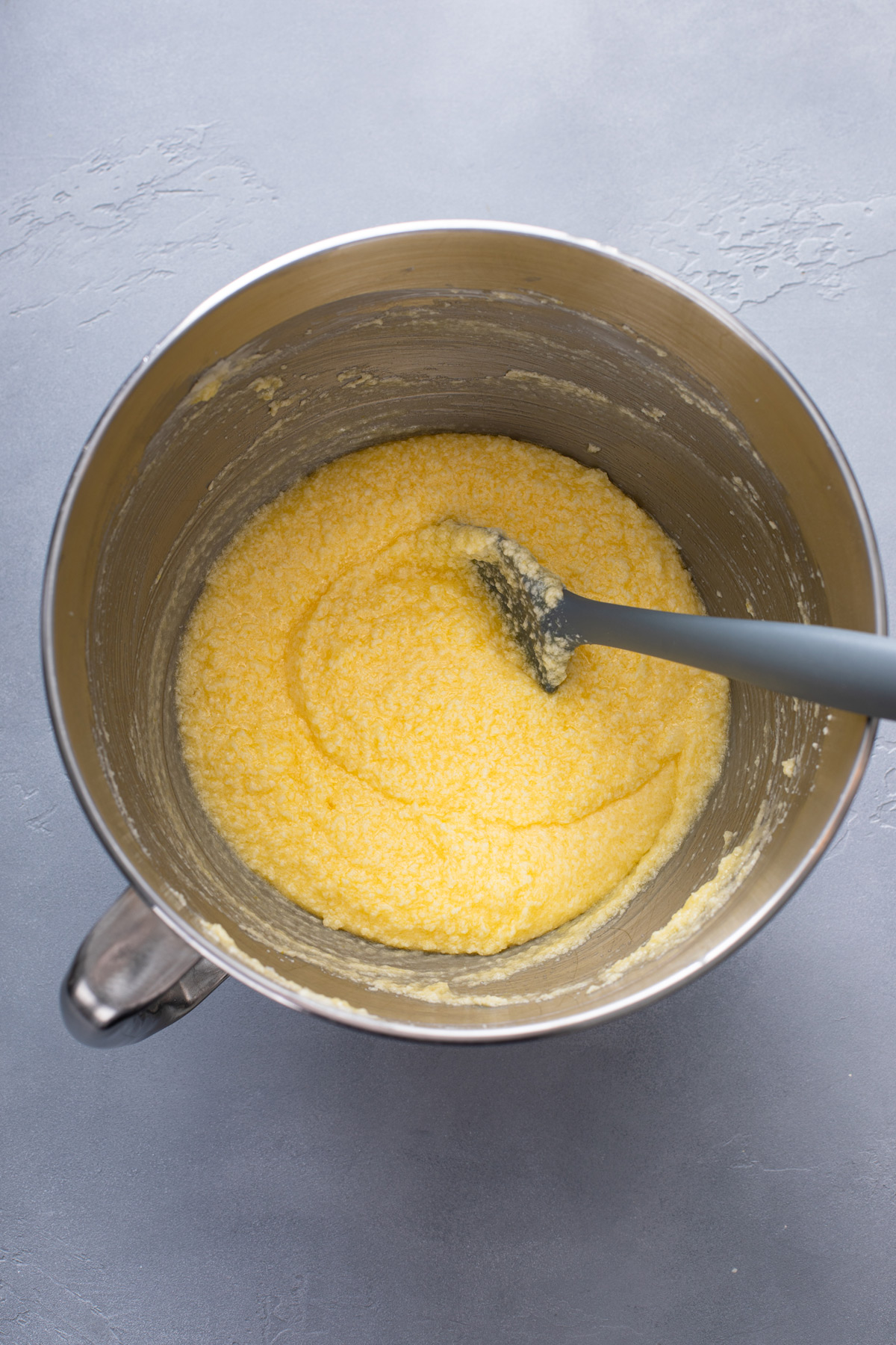 Butter, sugar, and eggs mixed together in a metal bowl.